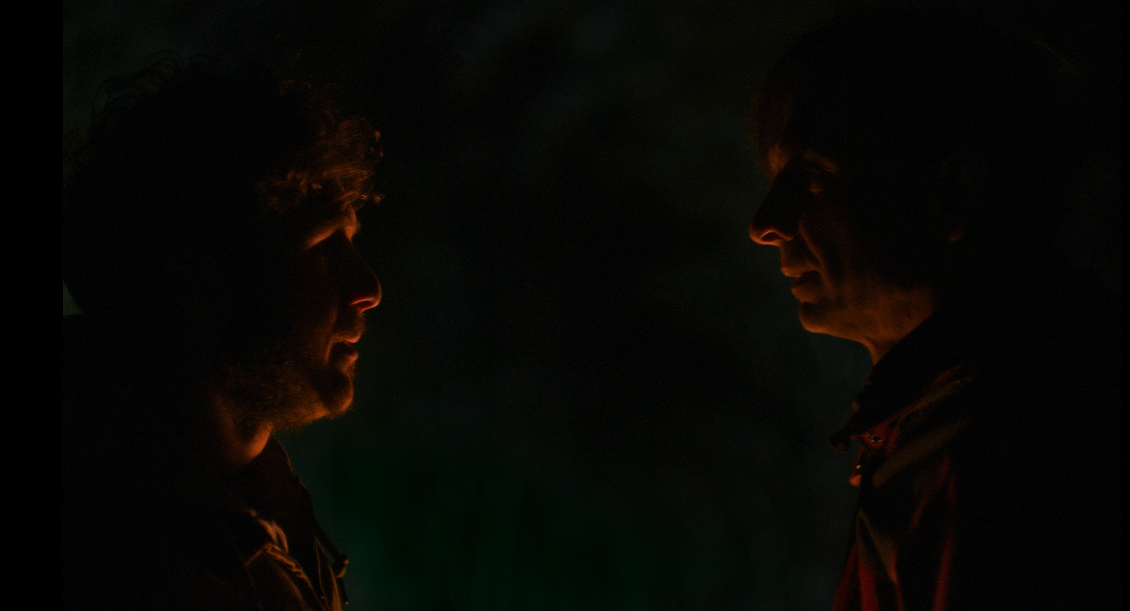 Low-key cinematic frame with layered depth and shadow.